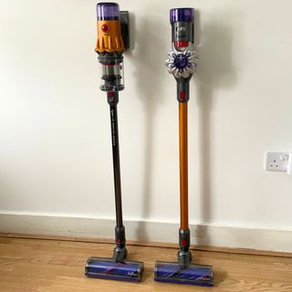 Dyson V12 and the Dyson V8 standing next to each other in front of a white wall