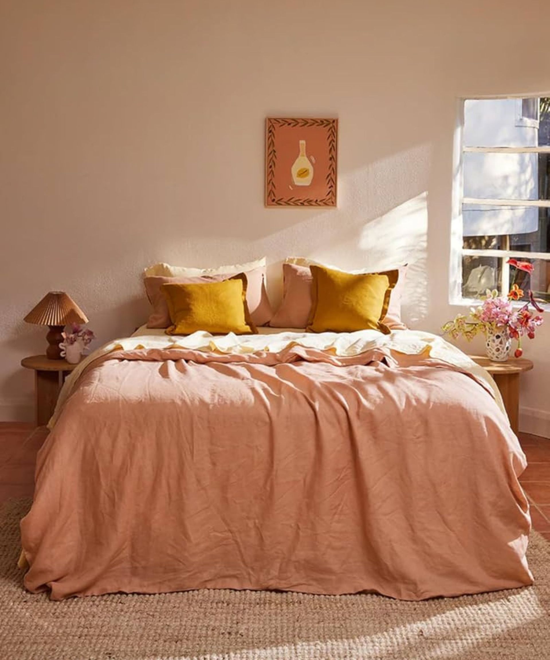 Orange and yellow bedding on a bed against cream walls.