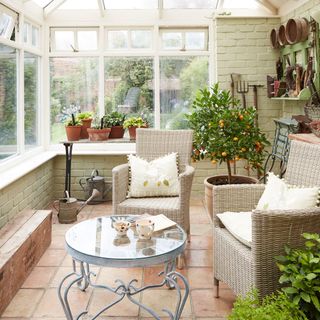 A conservatory with garden furniture and potted plants