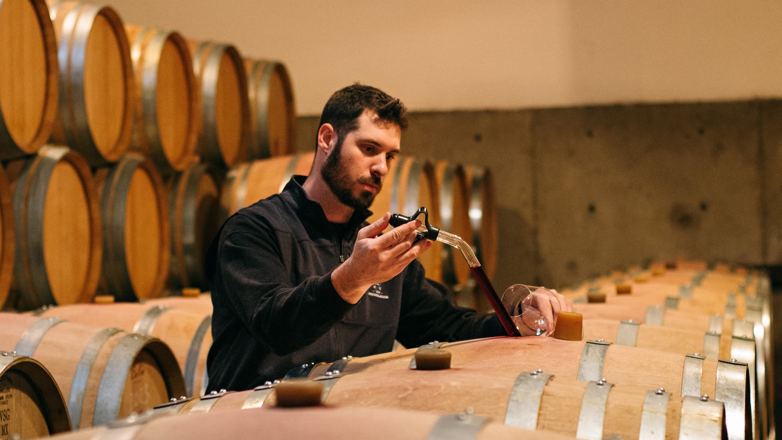 Beaux Fr&amp;eacute;res winemaker Damien Lapuyade in the winery's barrel cellar withdrawing a sample of red wine from a barrel.