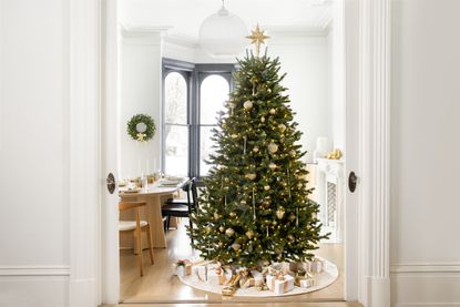 A bright living room with an artificial lit up Christmas tree in the centre