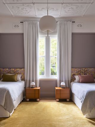 A bedroom with a two single beds, and lavender-painted walls