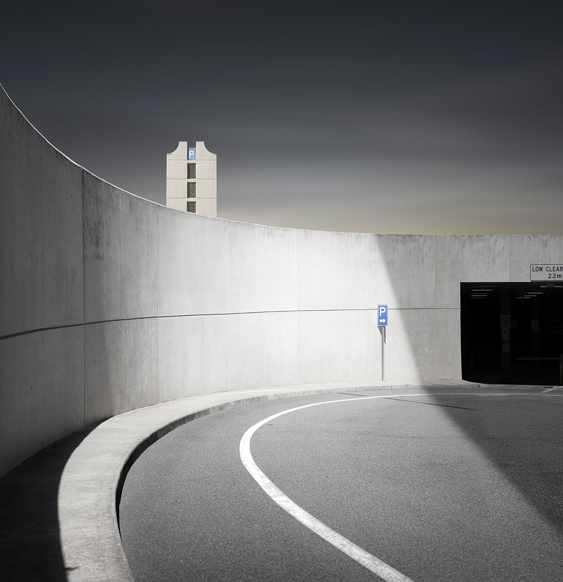 A curving road and wall with a building in the distance