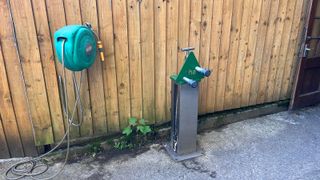 Hose and bike pump in front of fence