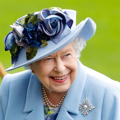 Queen Elizabeth wearing a blue coat and blue hat with roses 