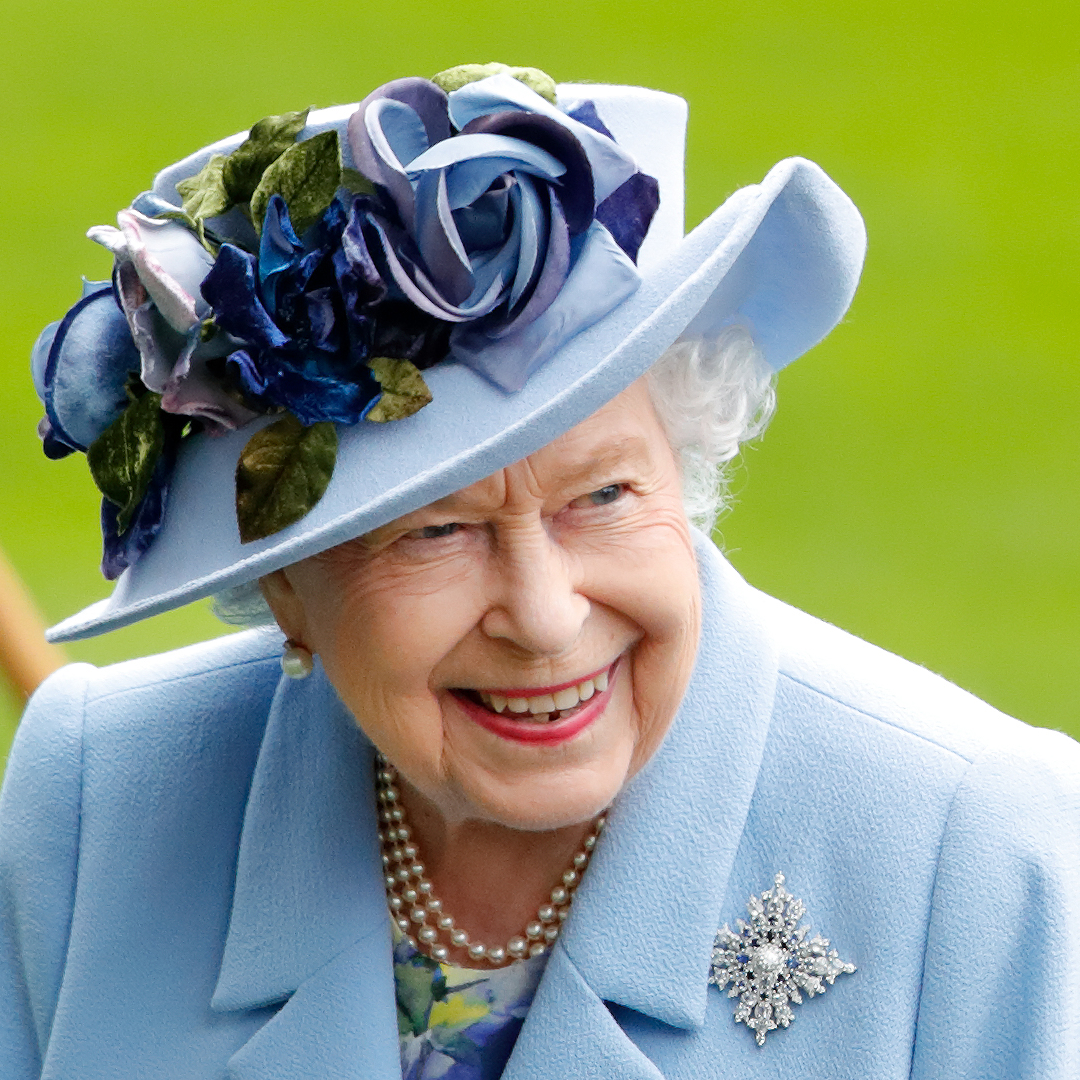 Queen Elizabeth wearing a blue coat and blue hat with roses 