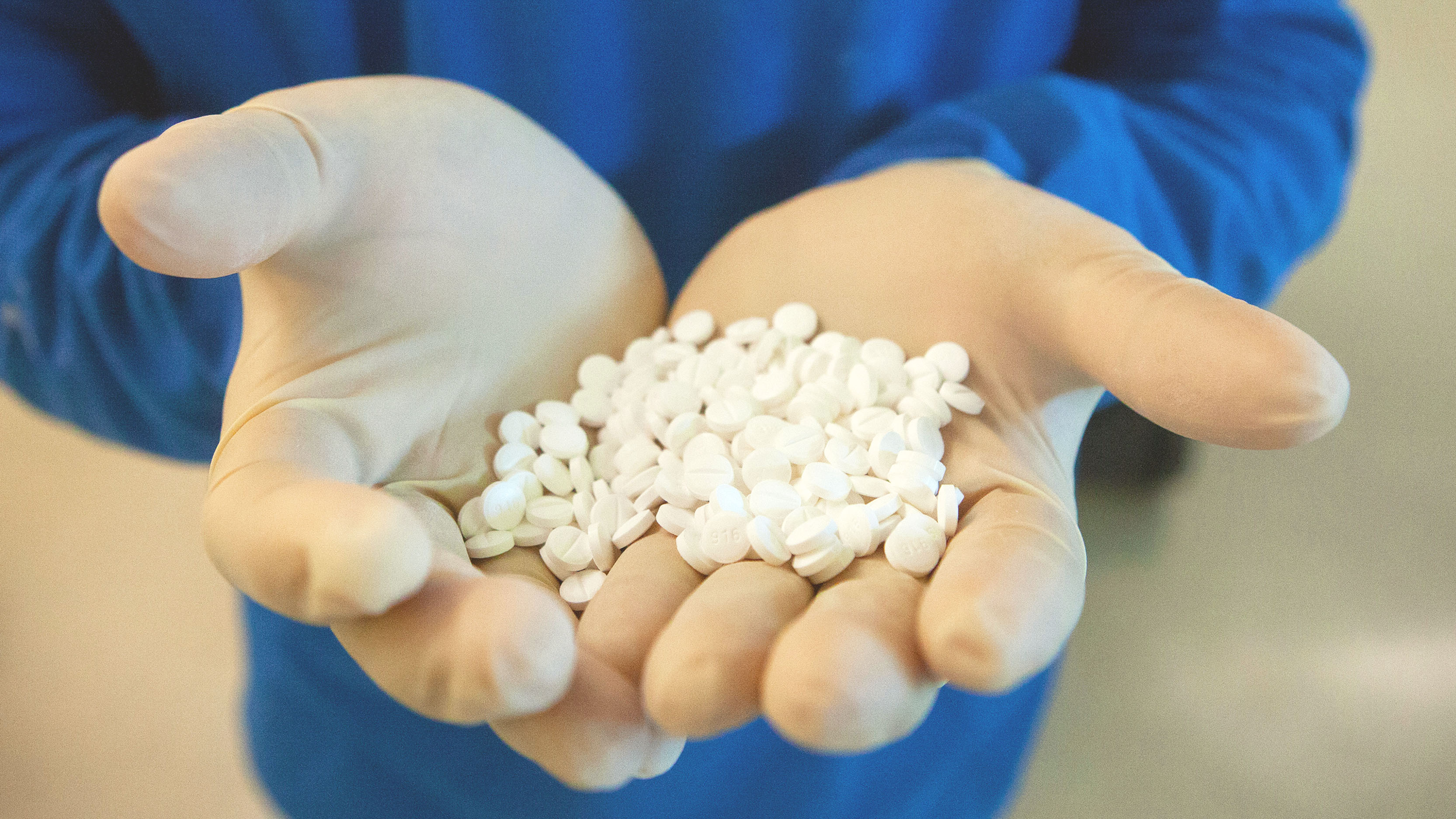 A pharmaceutical factory worker holds a handful of pills