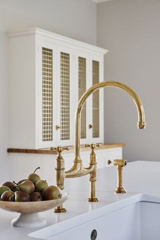 kitchen with a display of pears by a sink and antique brass tap