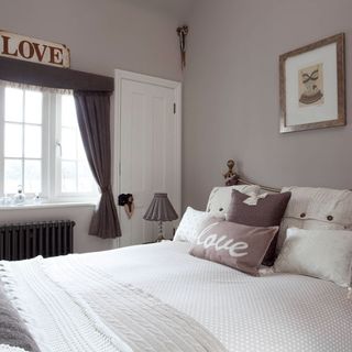 grey bedroom with cushions and walled picture
