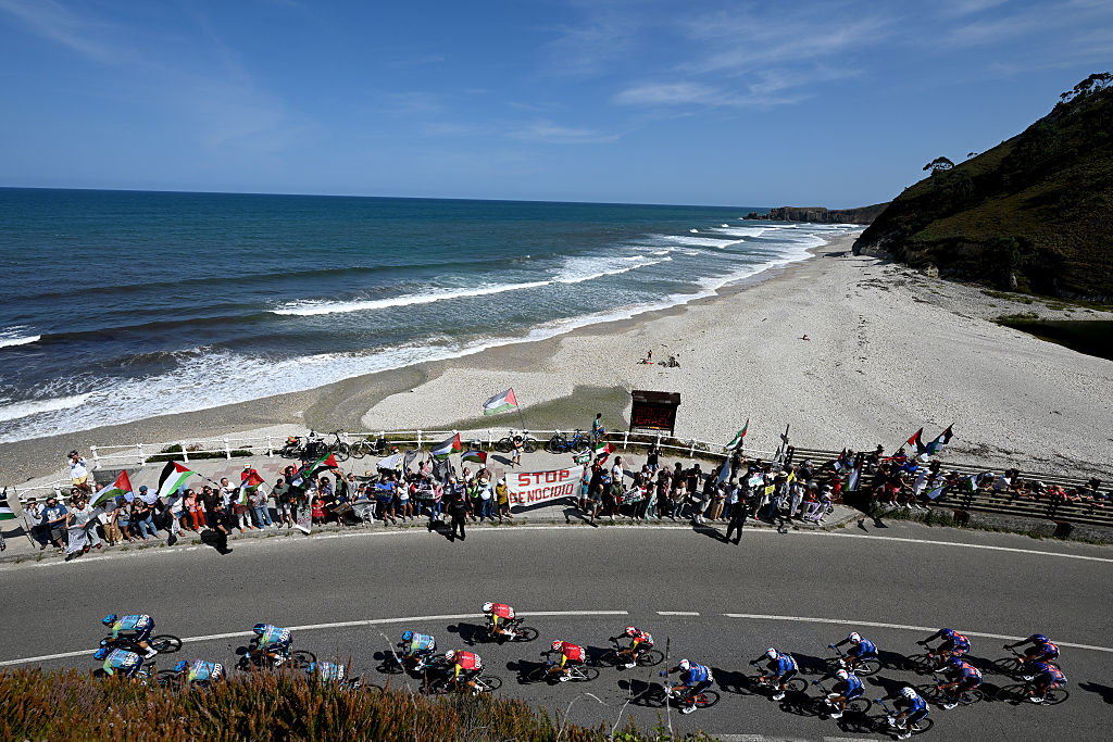 L&#039;ANGLIRU, SPAIN - SEPTEMBER 05: (L-R) Emanuel Buchmann of Germany and Team Cofidis, Stefan Kung of Switzerland and Team Groupama - FDJ and a general view of the peloton competing while pro-Palestinians protest during the La Vuelta - 80th Tour of Spain 2025, Stage 13 a 203.7km stage from Cabezon de la Sal to L&#039;Angliru 1556m / #UCIWT / on September 05, 2025 in L&#039;Angliru, Spain. (Photo by Dario Belingheri/Getty Images)