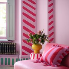 Pink walls with red and green contrast abstract stripes painted onto it. With striped accessories to finish the look