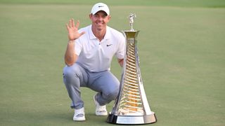 Rory McIlroy poses on one knee alongside the Race To Dubai trophy while holding up five fingers - the number of times he has won the prize