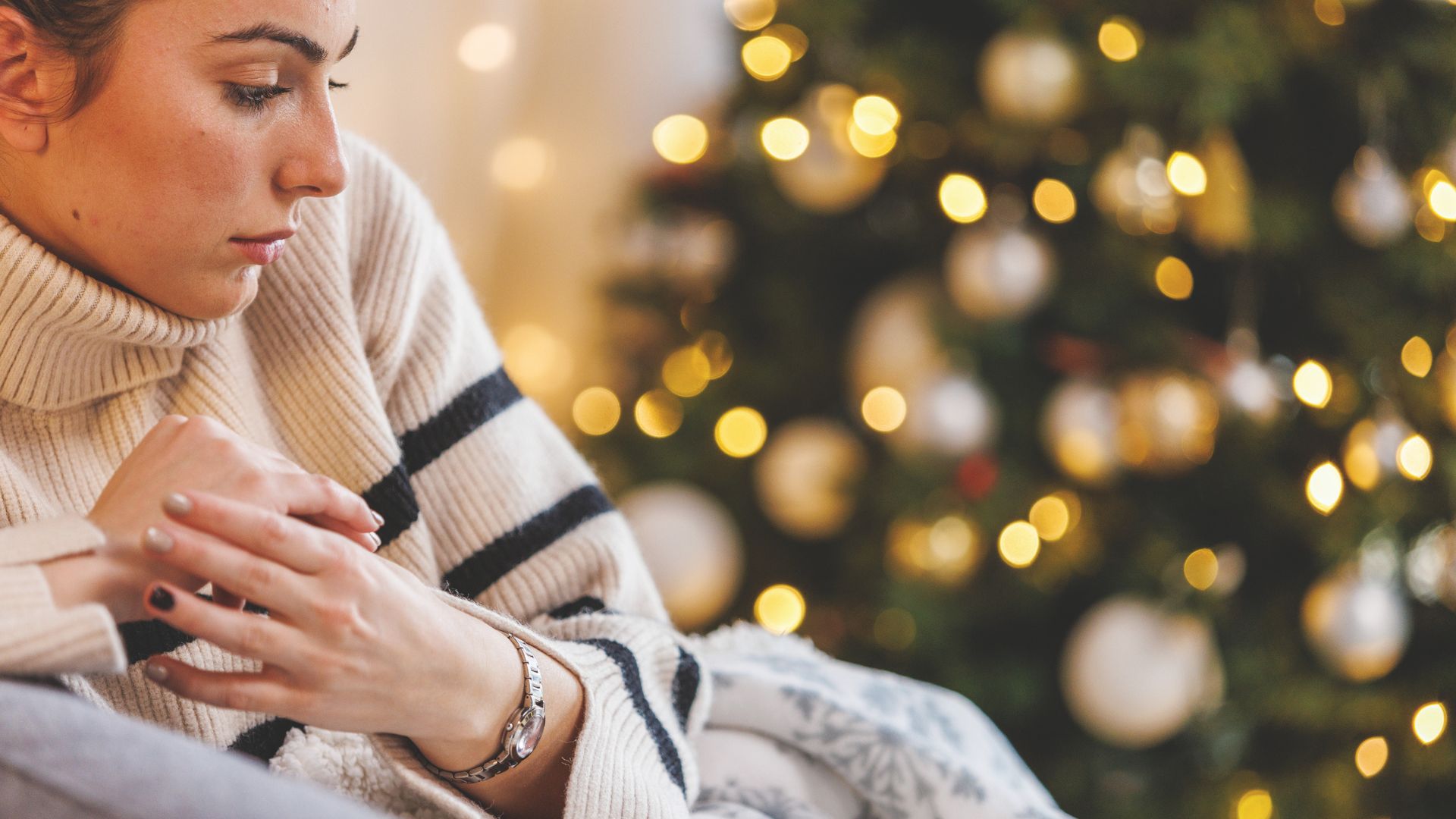 Woman looking worried in front of Christmas tree