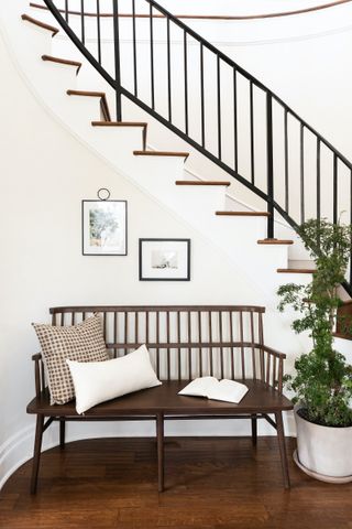 entrance hall with wooden bench and white stair, dark wooden floor, artwork and plant on floor