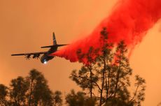 An airplane drops fire retardant.