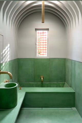 Bathroom with green titles and golden tap