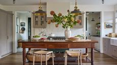A midimalist kitchen with warm white cabinets, a wooden freestanding island, and collected decor