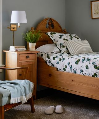 bedroom with pine bed, gray blue walls and floral bedlinen