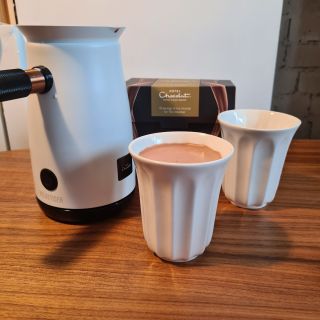 Hotel Chocolat Velvetiser with two mugs standing on kitchen counter, one mug filled with hot chocolate