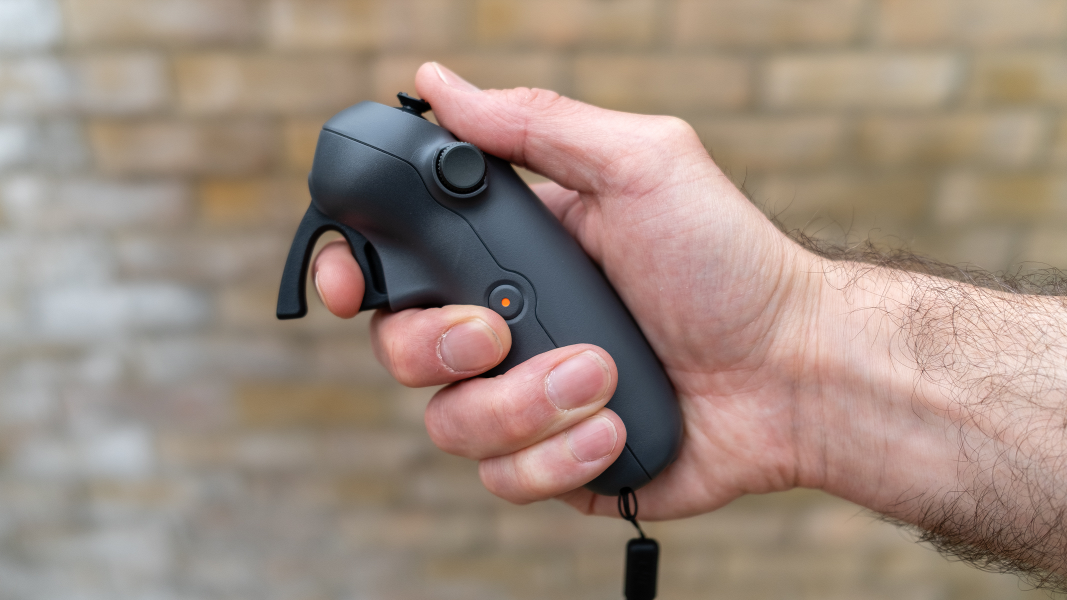 DJI RC Motion 3 Controller held in a man's hand with a defocused wall in the background