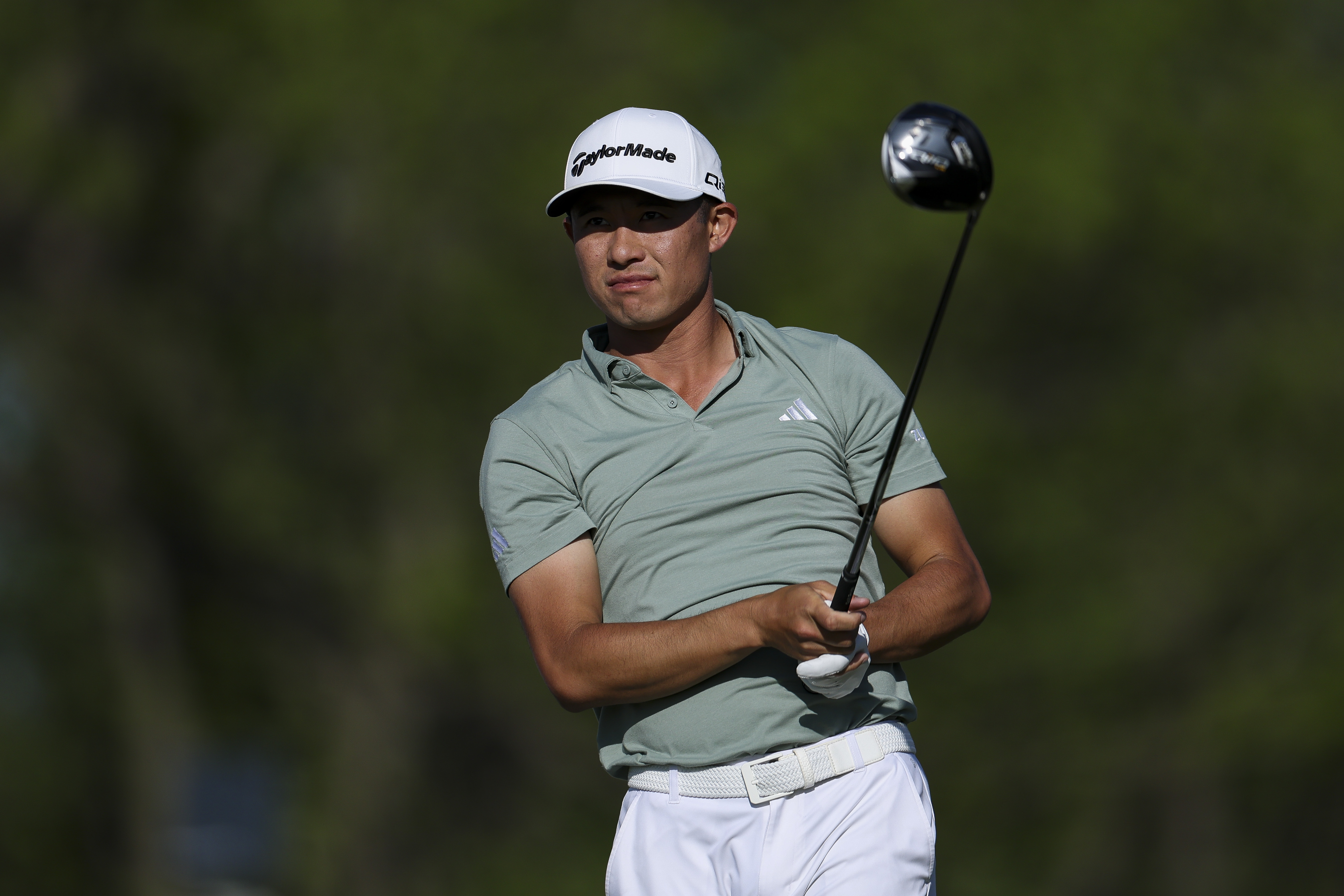 Collin Morikawa hits a tee shot and watches the flight of it