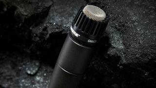 Close up of a Shure SM57 dynamic microphone leaning against a rock