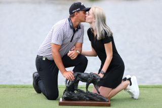 Christiaan Bezuidenhout and his wife kiss in front of the Alfred Dunhill trophy in 2022