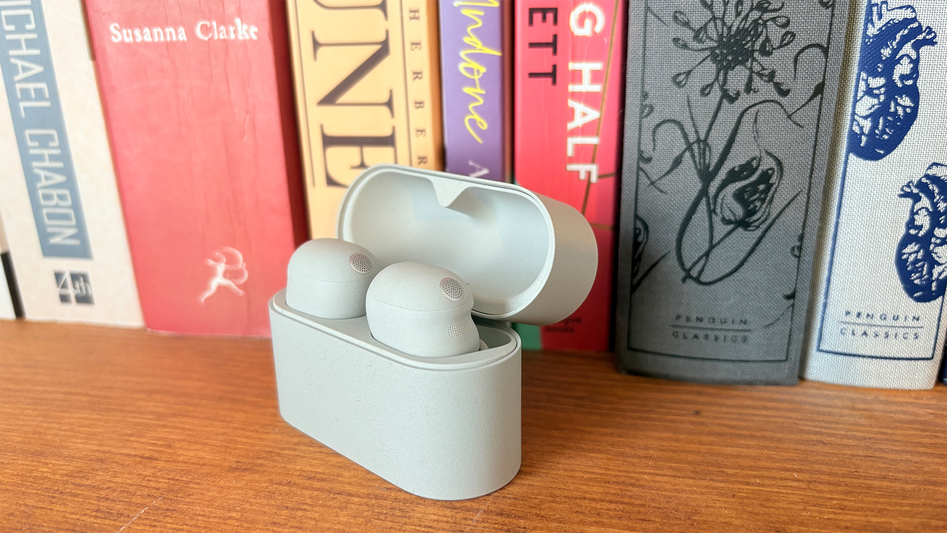 Sony WF-1000XM6 wireless earbuds in open case on bookshelf