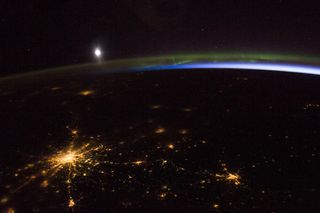 The green of the aurora borealis, the blue of airglow, the white of the moon and the yellow of city lights combine to create a dazzling spectacle in this astronaut photograph of Russia taken April 2, 2014.