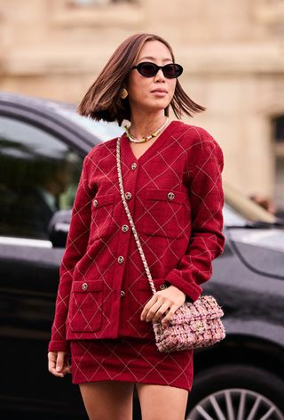 a street-style photo of a woman wearing a chanel red jacket and matching mini skirt with a vintage tweed chanel bag