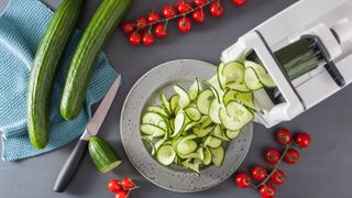 Vegetable spiralizer slicing cucumbers into a plate