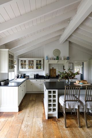 A kitchen with characterful wooden floors and a dining kitchen island with seats