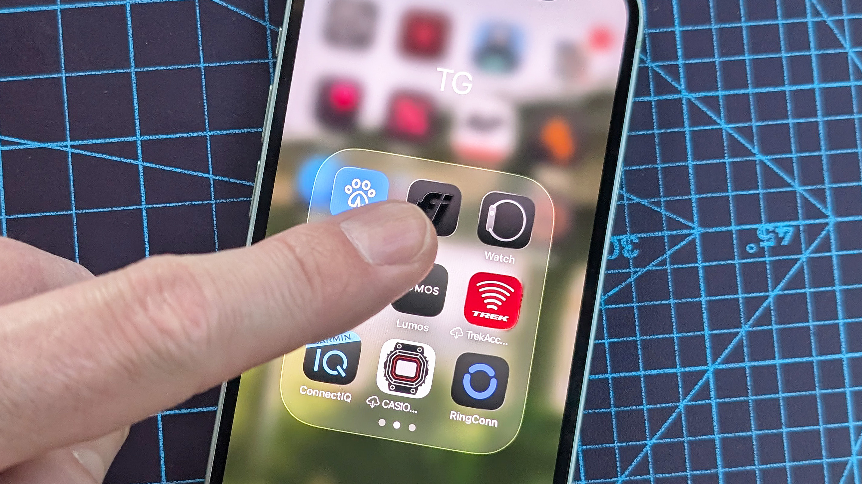 Close-up of an iPhone 12 Mini with a finger pointing at the Watch app