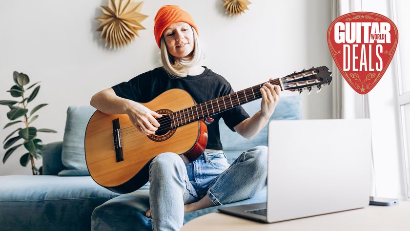 Woman wearing orange hat plays guitar in front of her laptop