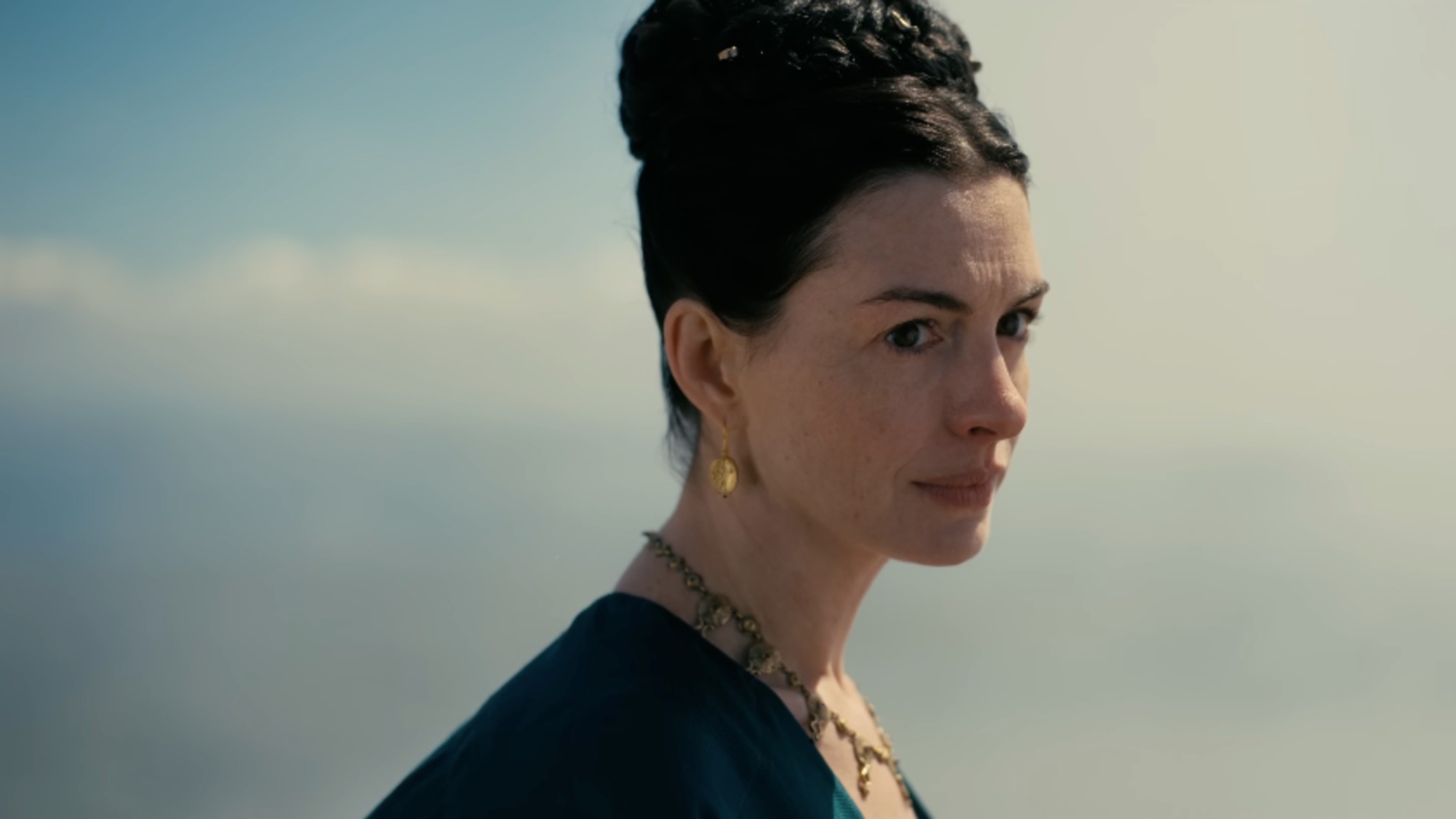A close up of Anne Hathaway with the sky and clouds behind her in The Odyssey