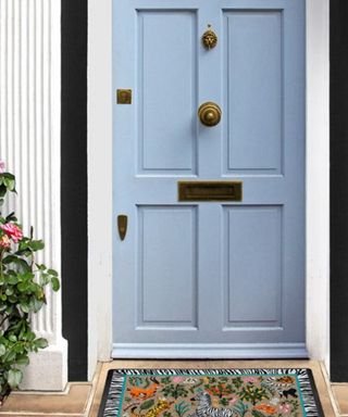 A blue door with a colorful door mat in front of it and a plant next to it