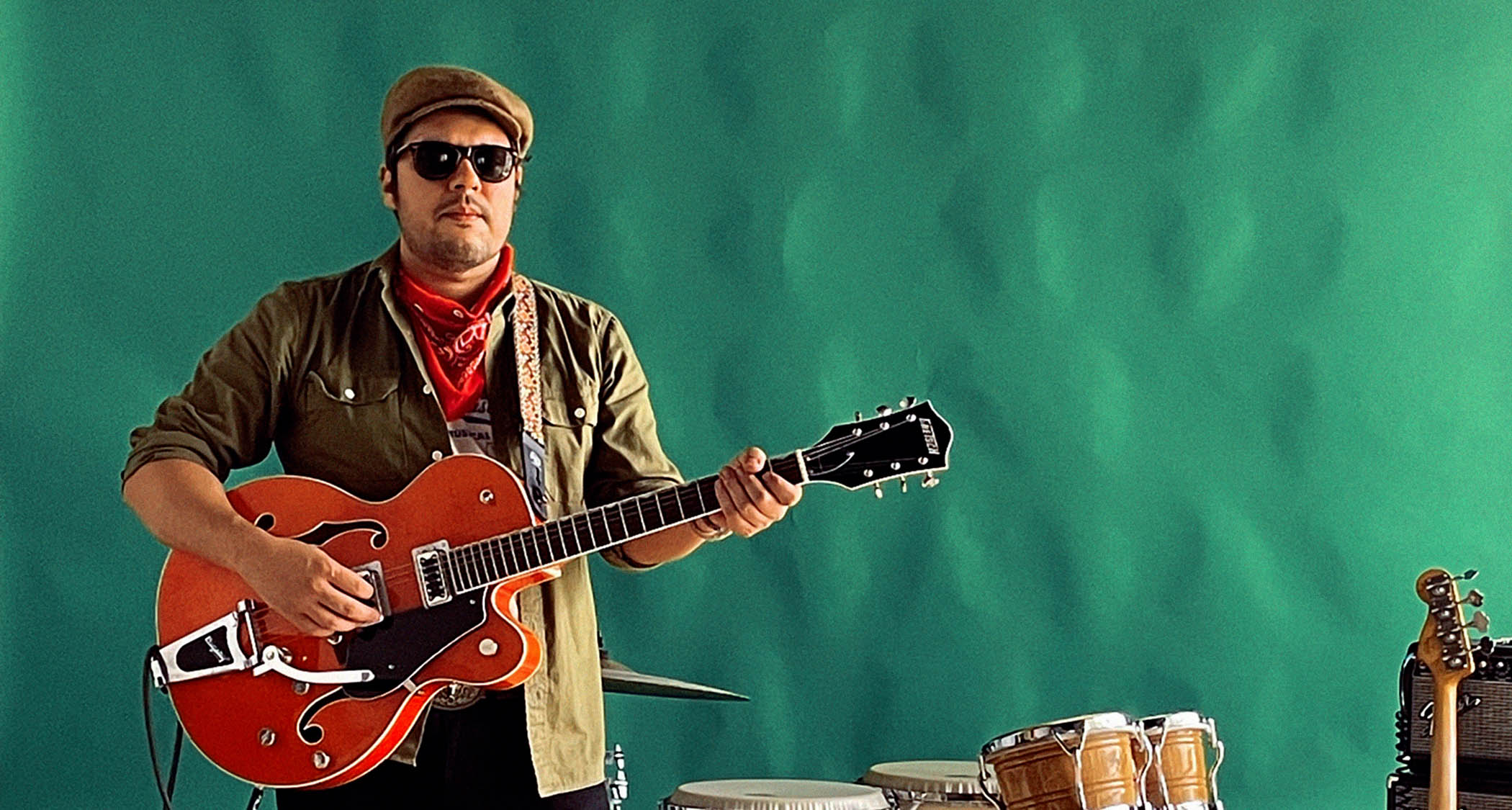 Mauro Lopez of the Animeros wears shades and poses with an orange Gretsch.
