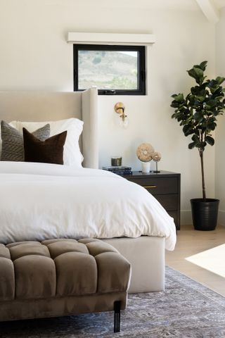 brown bed and ottoman in light bedroom