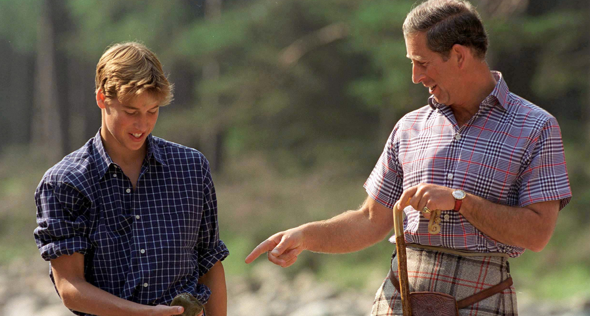 Prince William and Prince Charles standing on a rocky beach