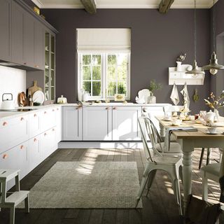 Kitchen with purple-grey walls and light blue cupboards, exposed wooden beams on the ceiling and matching wooden floorboards