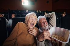 Cheerful senior couple watching funny movie at the theatre.