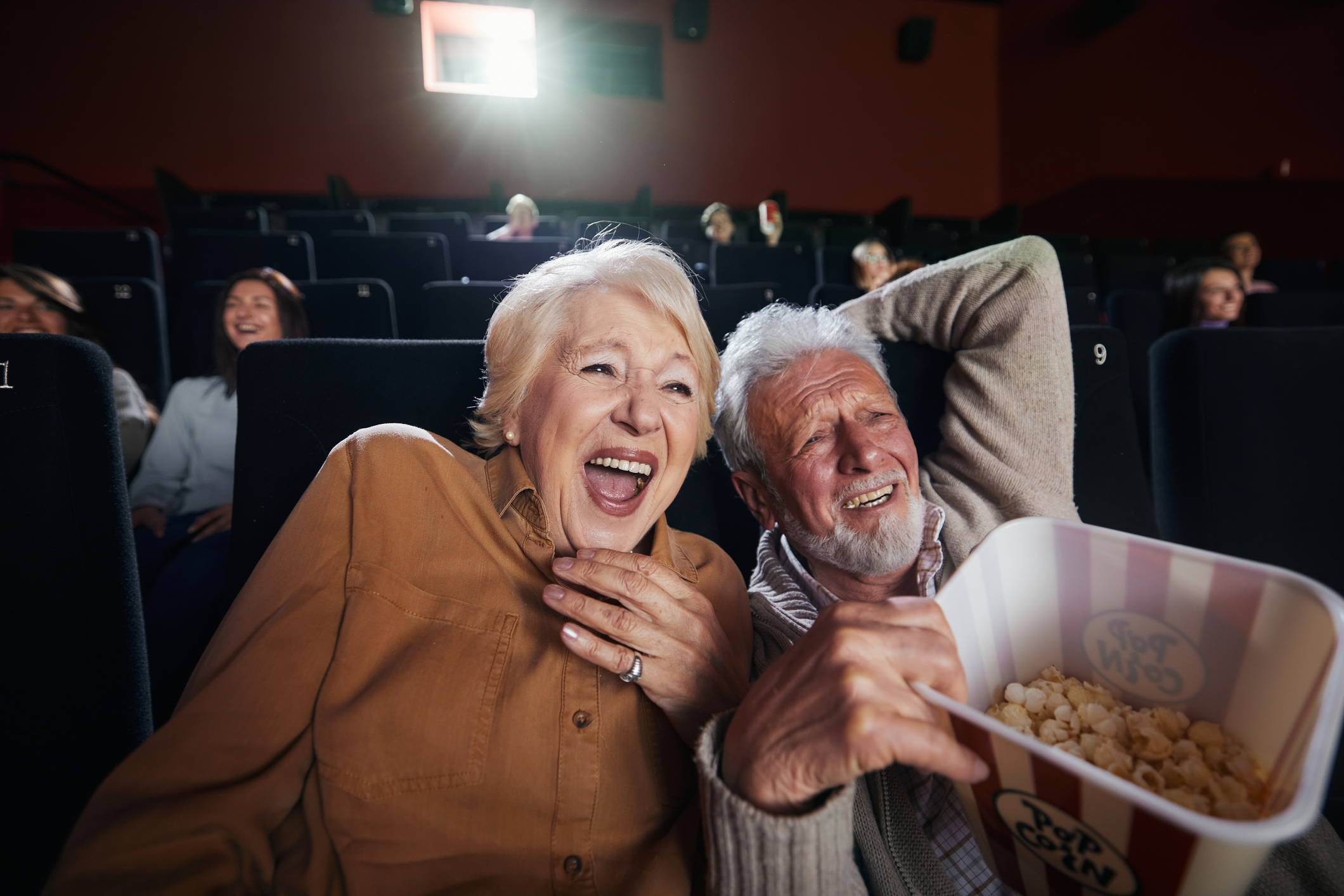 Cheerful senior couple watching funny movie at the theatre.