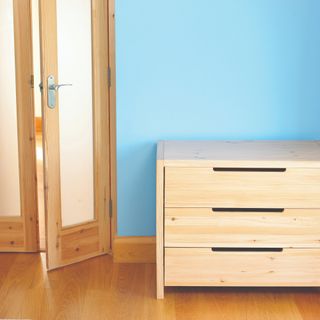 Wooden door with glass panels next to wooden chest of drawers