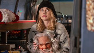 Alexandra Breckenridge sits in a van holding a Santa face mask