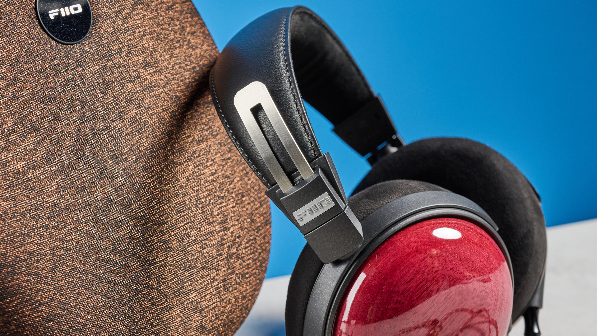 the fiio ft13 wired headphones with wood cups and copper cable photographed against a blue background