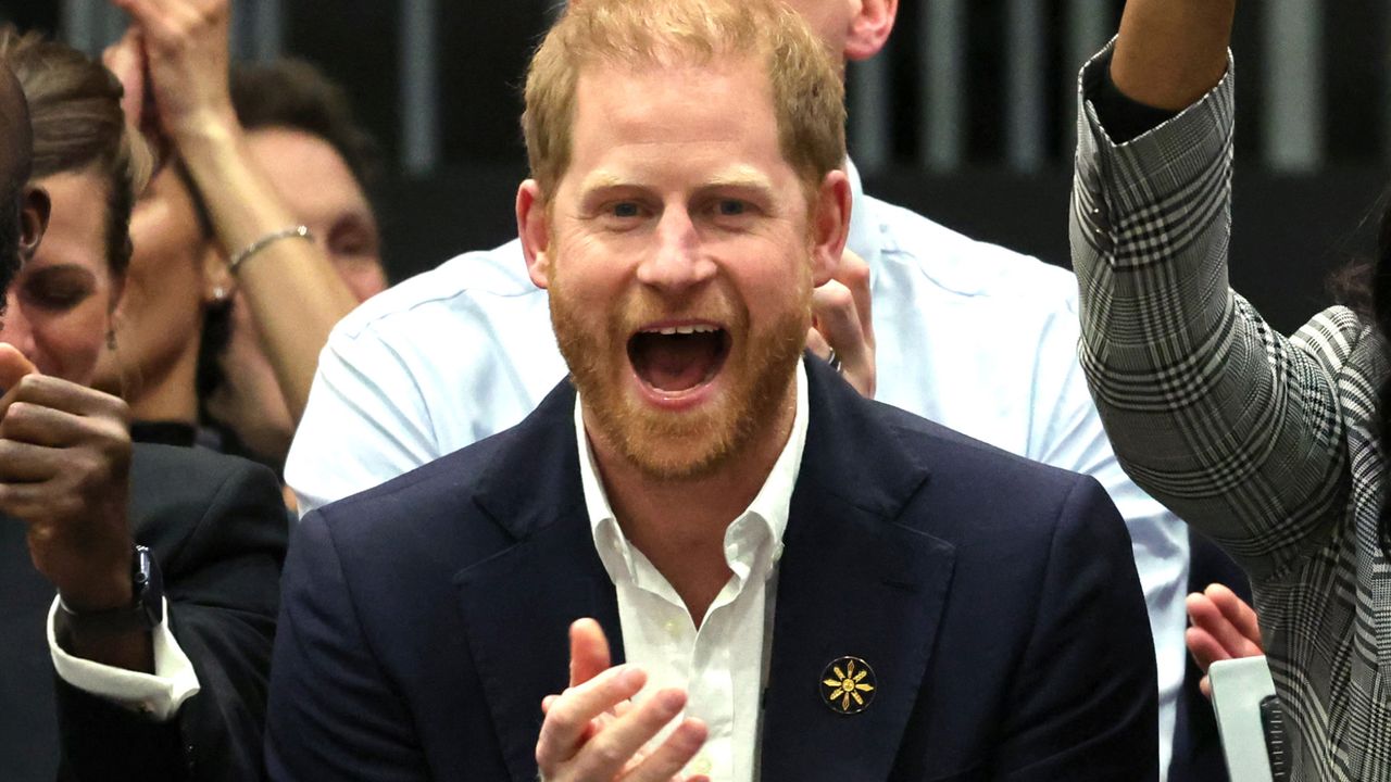 Prince Harry wears a white shirt and dark suit and cheers for the volleyball teams at the Invictus Games 2025