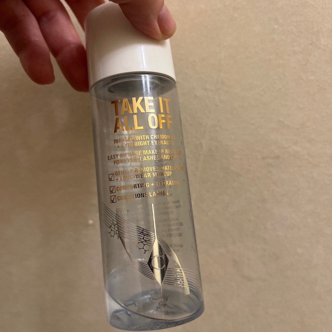 Hand holding empty bottle of Charlotte Tilbury Take It All Off Makeup Remover