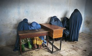 : Burqa-clad women wait to vote after a polling station runs out of ballots
