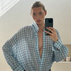 Model Elsa Hosk takes a mirror selfie wearing Mango's sheer blue checked shirt with a leather belt.