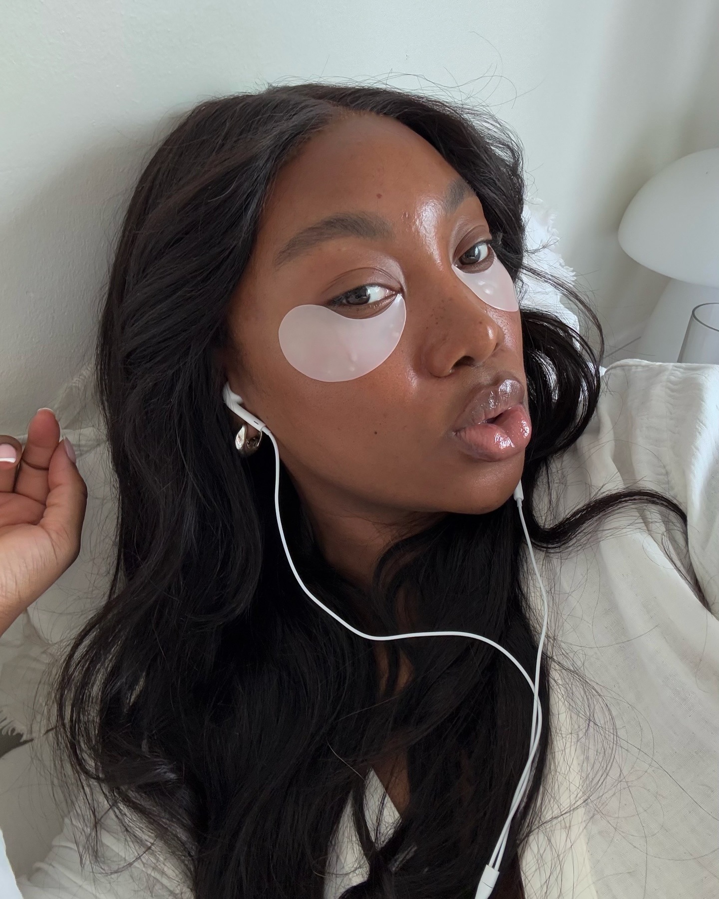 A woman taking a selfie wearing under-eye patches with a deep espresso brown hair colour
